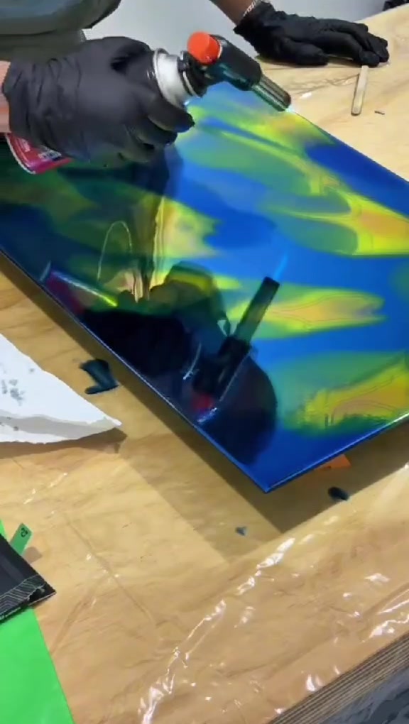 Maçarico passando sobre a superfície azul e amarela da peça.